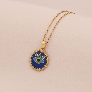 Détail macro du collier avec pendentif œil doré, émail bleu et bordure texturée