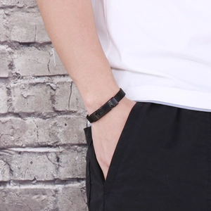 Close-up of black star-embossed metal plate on a minimalist braided silicone bracelet