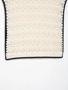 Gros plan détaillé du gilet en crochet ivoire montrant la maille ajourée et l'ourlet noir