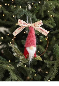 Close-up of a festive knitted Christmas gnome ornament hanging on a tree with warm bokeh