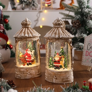 Detail of light-up Christmas snow globe with Santa Claus and reindeer on warm wood base