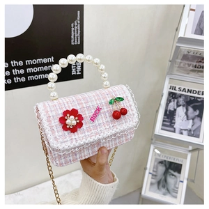 Detail of pink and white tweed mini bag with pearl handle and rock letter charm