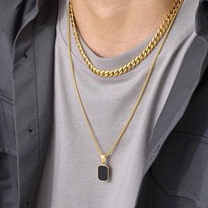 Detail of men's layered gold Cuban chain and black rectangular pendant necklace
