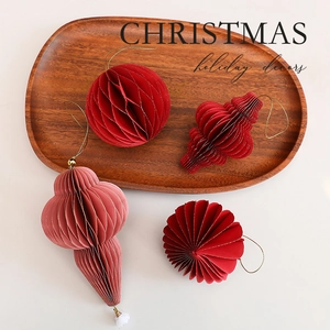Set of four crimson and pink honeycomb paper Christmas ornaments on a wooden tray decor