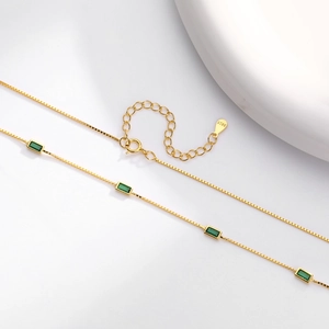 Detail view of gold-plated S925 silver box chain with rectangular emerald green stones
