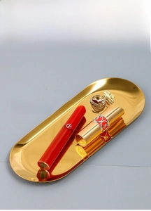 Close-up of golden stainless steel tray holding lipstick and rings in a 45-degree view