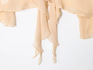 Close-up of beige chiffon blouse featuring delicate fabric texture and tie-up neckline detail