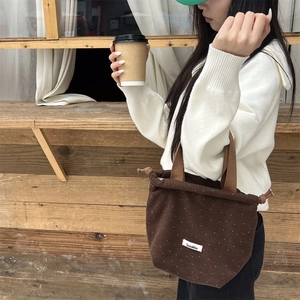 Detail of dark brown polka dot drawstring handbag with Sozakka tag in a lifestyle setting
