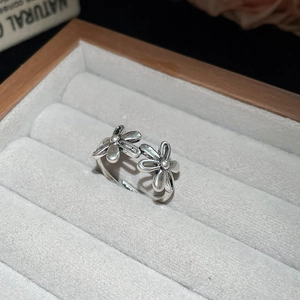 Detailed macro shot of vintage silver flower rings on grey velvet jewelry box padding