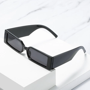 Trendy black rectangular narrow frame sunglasses on a minimalist white display stand