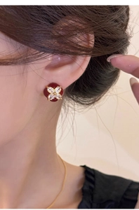 Macro shot of a vintage four-leaf clover stud earring with red enamel and gold plating