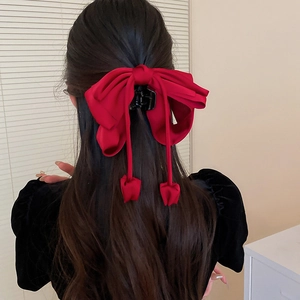 Vue arrière d'une grande pince à cheveux en tissu bordeaux avec de longs pompons