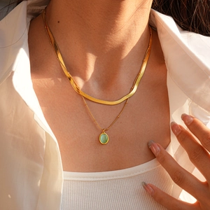 Détail du collier à double rang doré avec pendentif opale verte porté par un modèle
