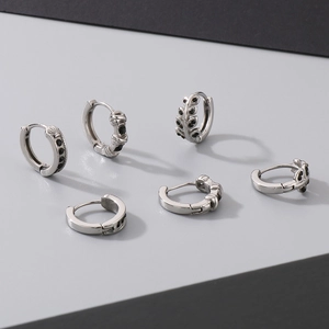 Detail of silver titanium earrings set with black zircon in leaf and punk patterns