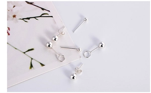 Macro detail of S999 silver ball stud earrings set on a floral card display