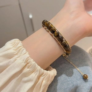 Detail of vintage tiger eye stone beaded bracelet with golden metal frame on wrist