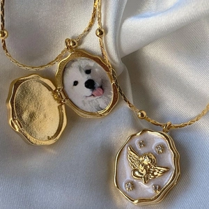 Dettaglio del medaglione d'oro aperto con foto di cane e angelo inciso su madreperla