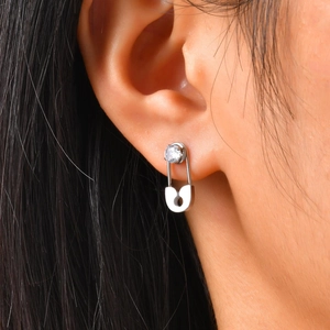 Macro detail of silver safety pin earring with sparkling zircon on model's ear