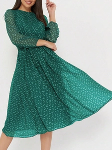 Vue dynamique d'une robe midi verte à pois montrant la fluidité de la coupe trapèze