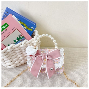 Detailed macro view of pink tweed girls handbag with oversized bow and pearl handle