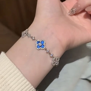 Detail shot of a silver clover bracelet with blue enamel and zircon inlay on a wrist