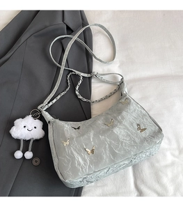 Detail of grey-blue shoulder bag with crinkled texture and silver butterfly charms