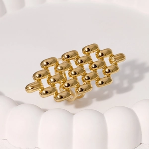 Modern wide hollow braided gold stainless steel ring displayed on white wavy tray