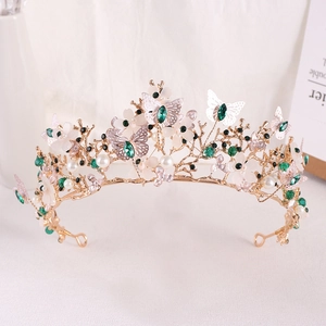 Detail of golden baroque tiara with green crystals, acrylic flowers and silver butterflies