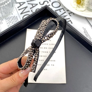 Close-up of black headband with luxury rhinestone bow on elegant magazine background