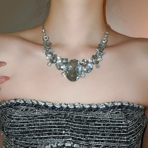 Close-up of a large silver crystal teardrop necklace on a model showing sparkling details