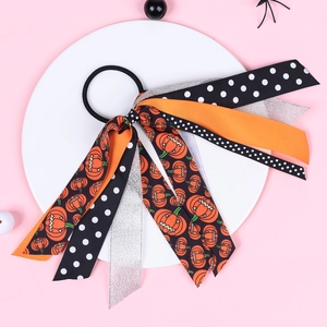 Close-up of Halloween ribbon hair tie with pumpkin patterns and silver glitter on white tray