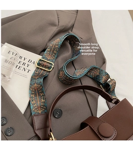 Detail of vintage patterned wide fabric strap on a dark brown leather bucket bag