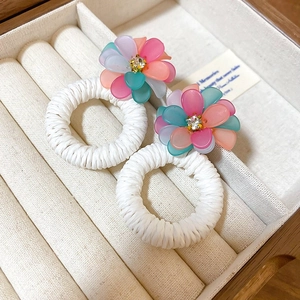 Detail of colorful woven flower earrings with frosted rainbow petals and crystal centers