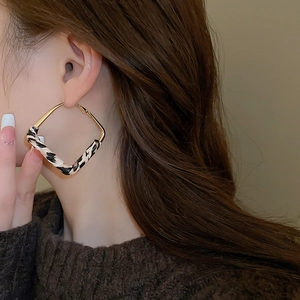 Detail shot of leopard print leather wrapped gold square hoop earrings on a model