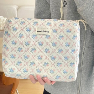 Détail d'une trousse de toilette matelassée à motifs floraux avec étiquette Jolly House