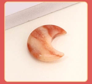 Macro detail of crescent moon pendant with polished red orange agate stone texture