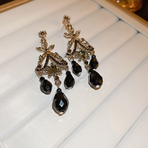 Close-up of vintage court style earrings with gold metal, crystals and black teardrop beads