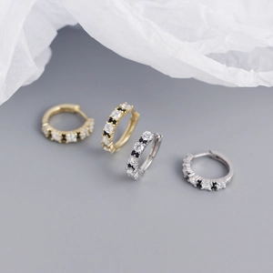 Macro shot of silver and gold hoops with black and white cubic zirconia accents