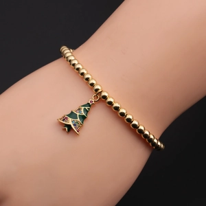 Dettaglio del bracciale a sfere dorate con ciondolo a forma di albero di Natale smaltato