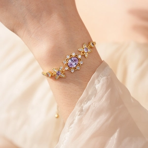 Detail of vintage gold flower bracelet with purple gemstones on a model's wrist