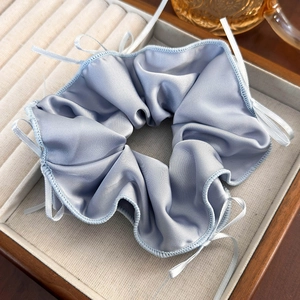 Close-up of blue plaid silk scrunchie with lace edge in a beige jewelry gift box