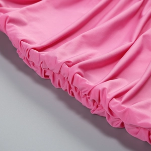 Close-up of pink ruched fabric detail with elastic cuff stitching on long sleeve dress
