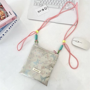 Detail of light green butterfly crossbody bag with pink rope strap on marble desk