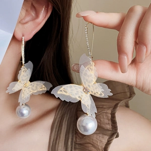 Close-up of long drop earrings with mesh butterfly wings and large white pearls