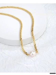 Detail view of gold Cuban chain necklace with a large white freshwater pearl pendant