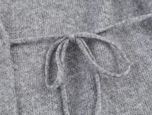 Close-up of grey knitted wool fabric texture with detailed lace-up ties on the coat