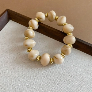 Macro shot of cream marble beads with gold metallic spacers on a retro beaded bracelet