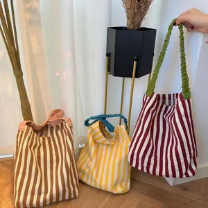 Detailed view of color-block striped knit tote bags with unique ruffled contrast handles