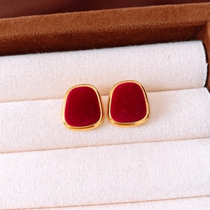 Macro detail of red flocked earrings with gold metal frame on a velvet jewelry display