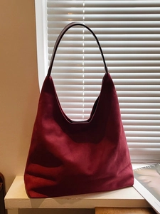 Minimalist burgundy suede hobo tote bag with dark leather strap on white windowsill